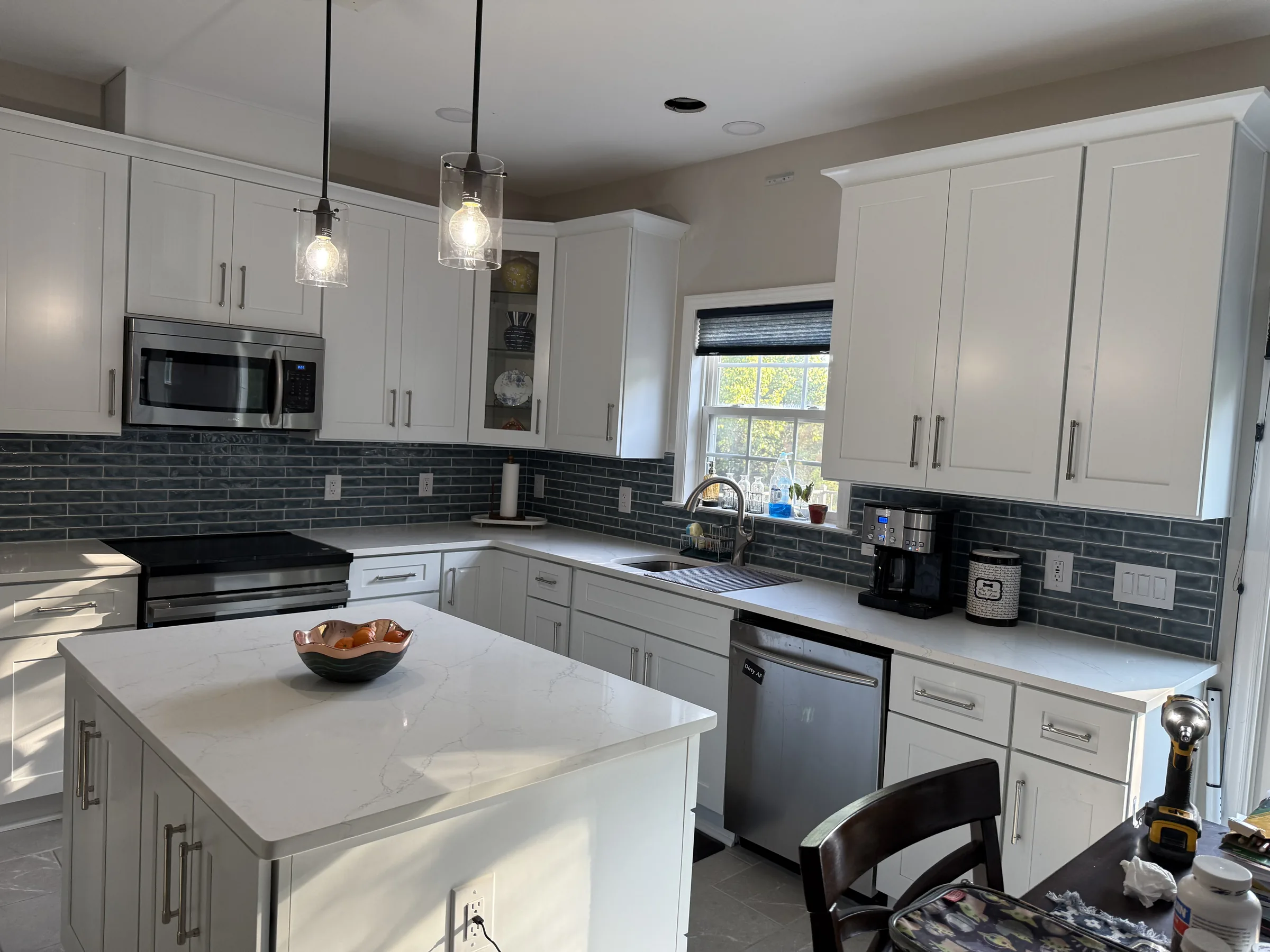 White shaker kitchen with dark slate subway tile backsplash and quartz island