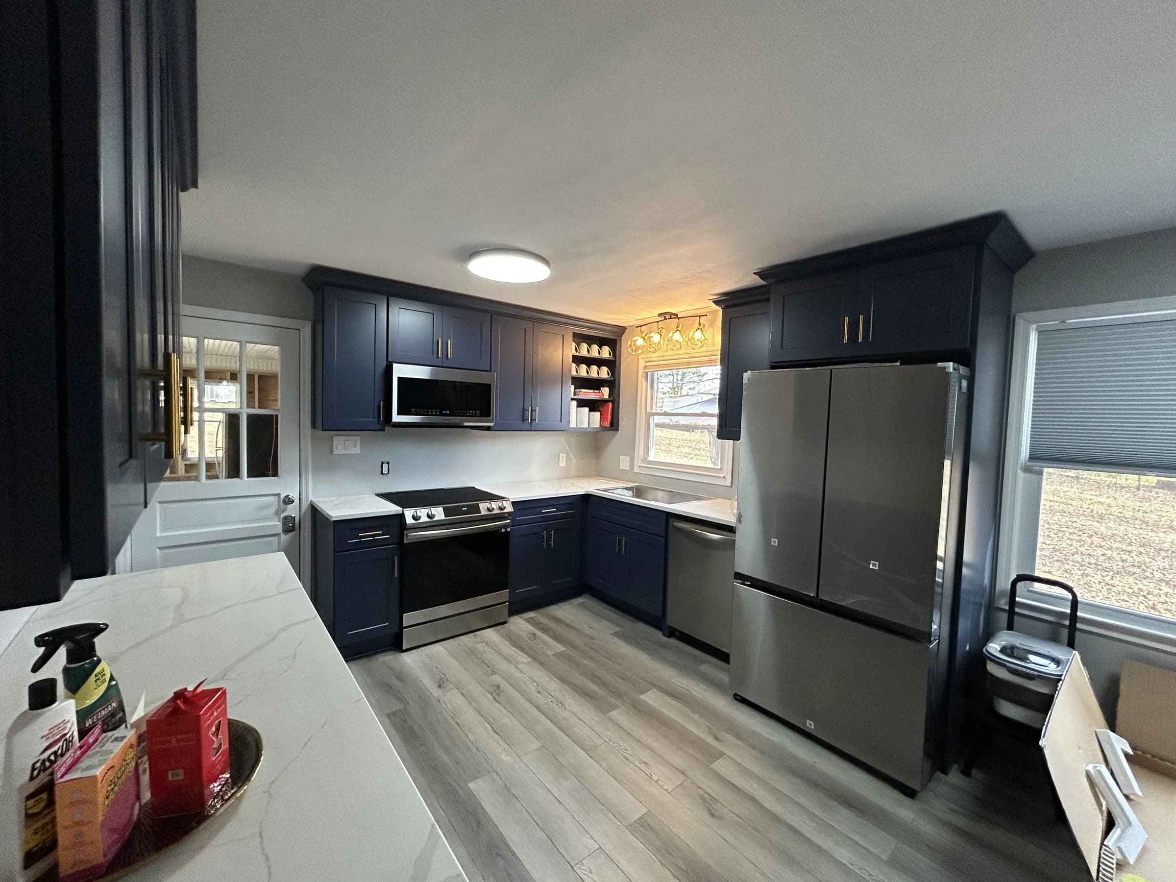 Navy shaker kitchen with white quartz waterfall island and brass pulls - photo 1
