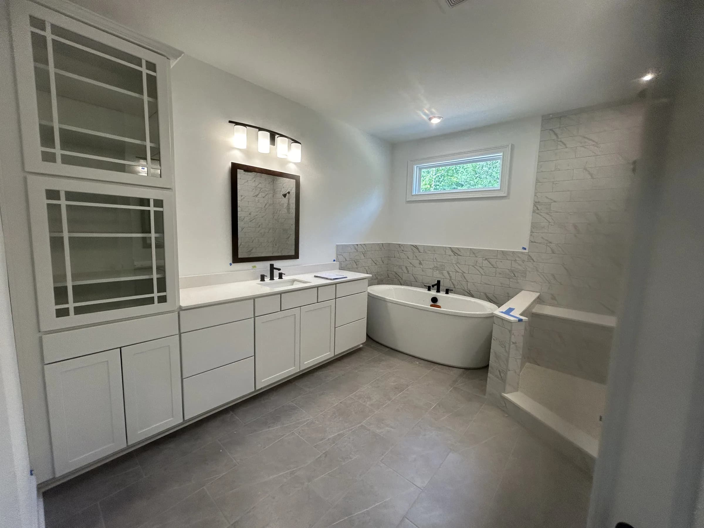 Finished bathroom with freestanding tub, vanity, marble-style wall tile, and gray floor tile