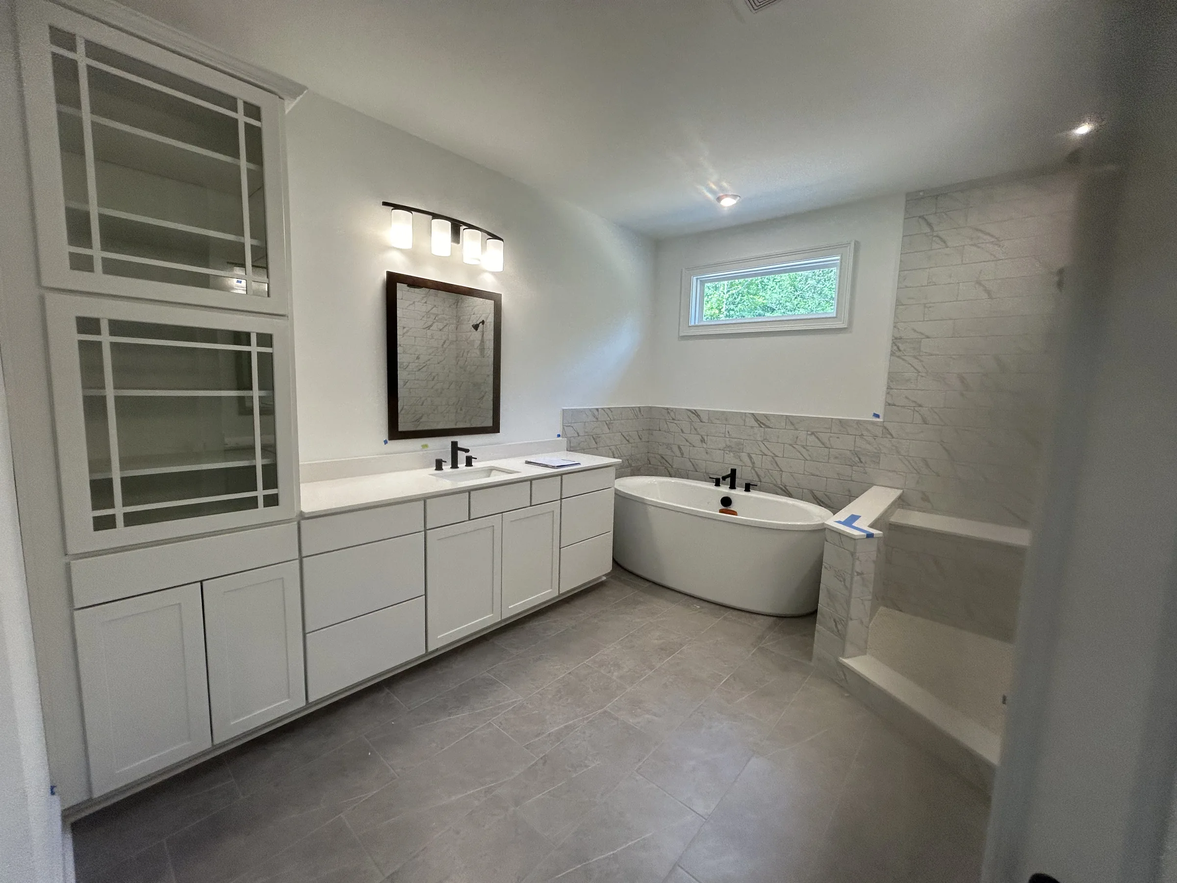 Finished bathroom with freestanding tub, vanity, marble-style wall tile, and gray floor tile